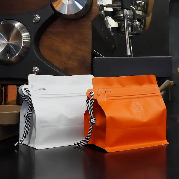 白とオレンジの150gストックコーヒーバッグ(前面からはランヤード付き)