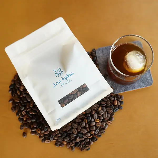 焙煎コーヒー豆の上にコーヒーバッグを平らに置き、アイスコーヒーの隣に置いて商品を表現します
