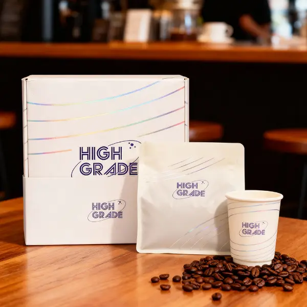 プレミアムカスタムブランドのコーヒーボックスが、カフェの環境でコーヒーバッグとカップを添えて展示されています