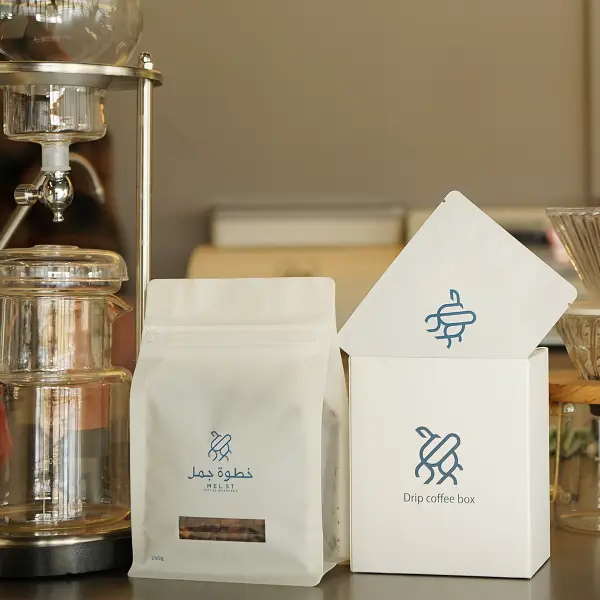 プレミアムなカスタム紙箱とコーヒーバッグがカフェ環境でブランディングディスプレイとして展示されています
