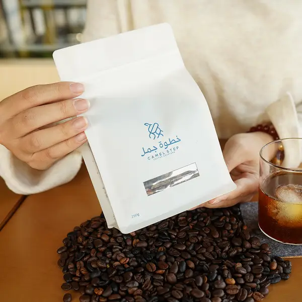 ライフスタイルの場で、印刷された紙箱が入った白いコーヒーバッグを持つお客様がいます